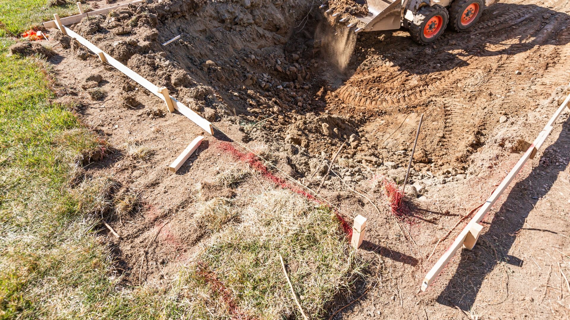 Construction site with excavated hole and wooden markers for foundation work